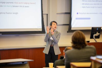 A conference speaker motions with her hands while presenting to an audience